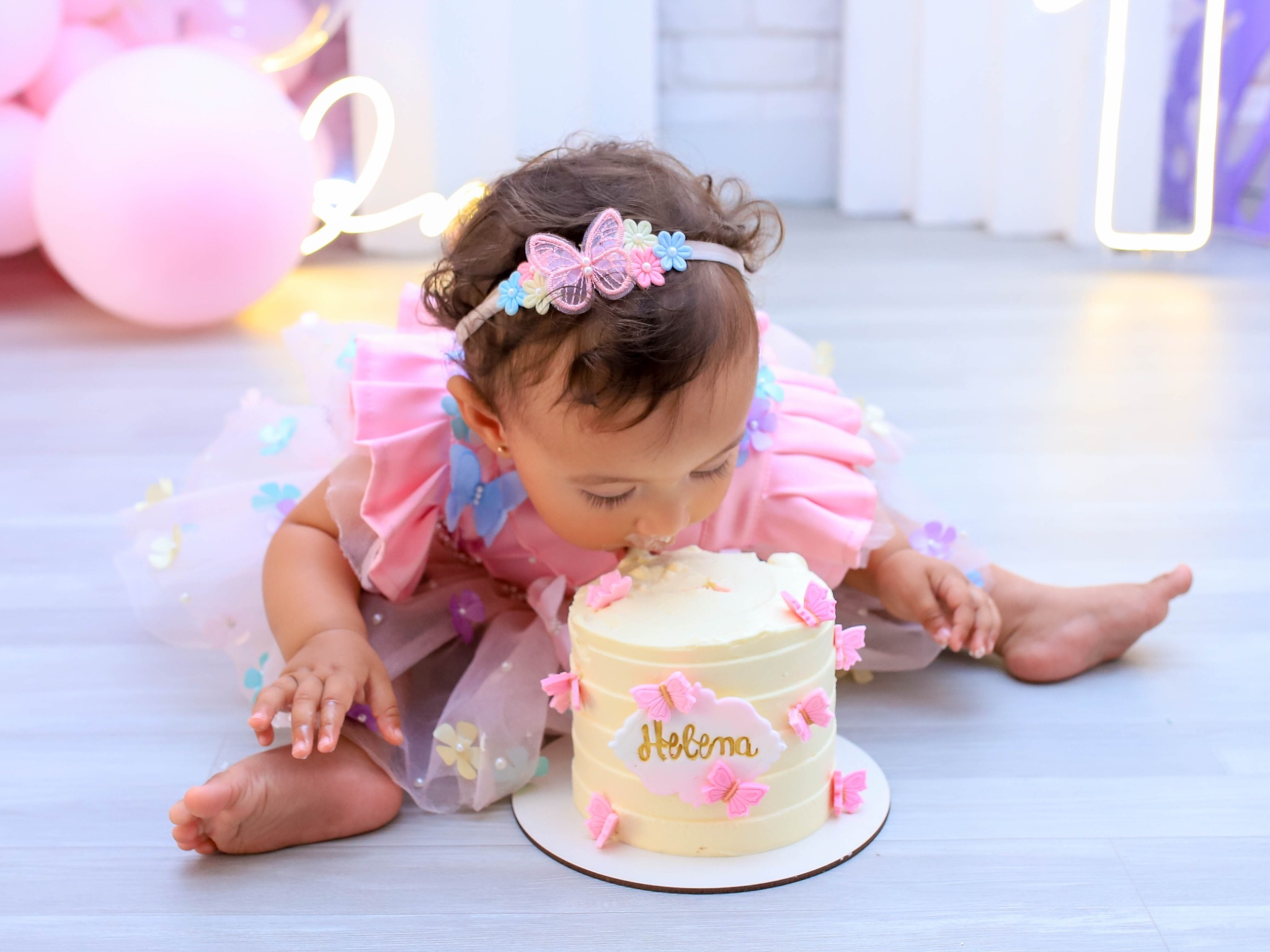 Menina em ensaio Smash the Cake com bolo e vestido rosa